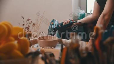 陶器-主人正在创意车间用建筑吹风机烘干一个碗。